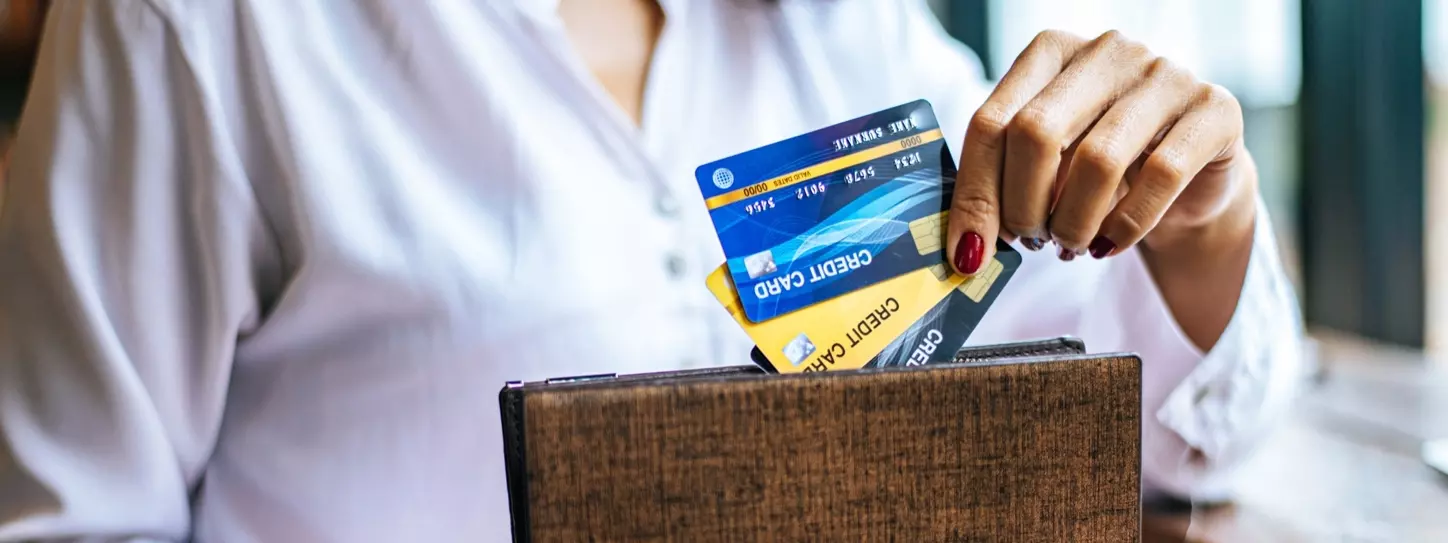 ผู้หญิงถือบัตรเครดิตหลายใบพร้อมกระเป๋าสตางค์สีน้ำตาล