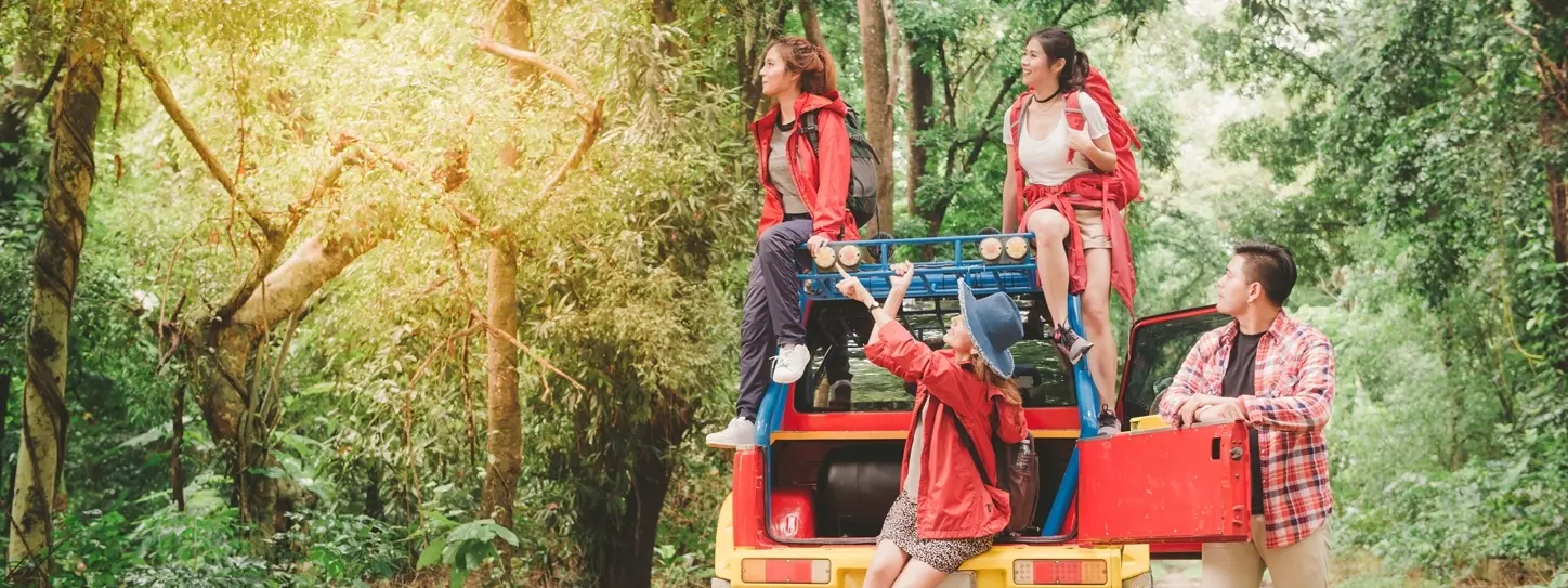 นักท่องเที่ยวชายและหญิงจอดรถชมความเขียวขจีของพื้นป่า