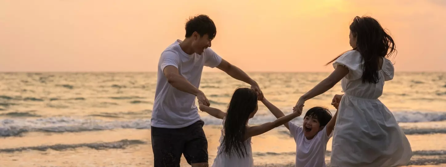 ครอบครัว 4 คน พ่อแม่ลูกกำลังเล่นสนุกที่ชายหาด