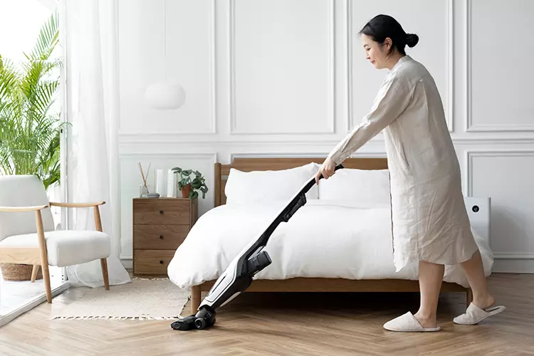 ผู้หญิงกำลังใช้เครื่องดูดฝุ่นไร้สายทำความสะอาดบ้าน