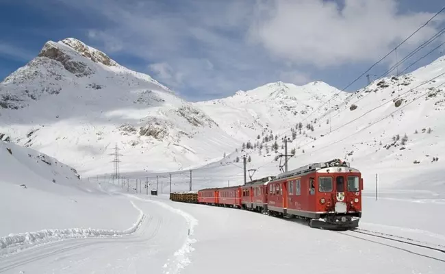 รถไฟวิ่งท่ามกลางหิมะที่ล้อมรอบด้วยภูเขา