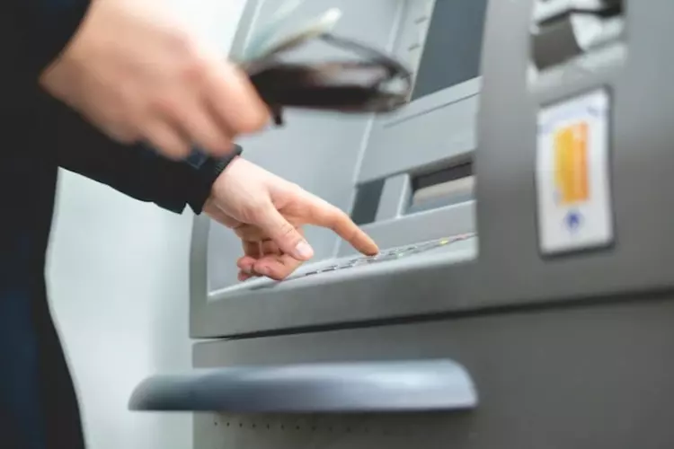 คนกำลังกดเงินจากบัตรกดเงินสดที่ตู้ ATM 