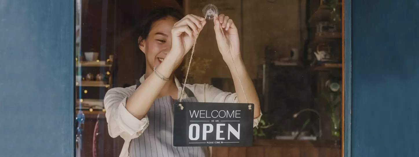 ผู้หญิงหมุนป้ายเปิดร้าน