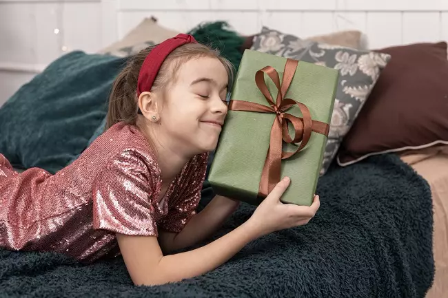 เด็กผู้หญิงถือกล่องของขวัญพร้อมยิ้มดีใจ