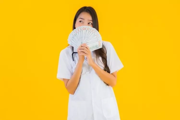 ผู้หญิงยืนถือธนบัตรจำนวนมากในมือ 