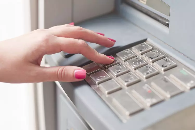 ผู้หญิงกำลังกดเงินที่ตู้ ATM  