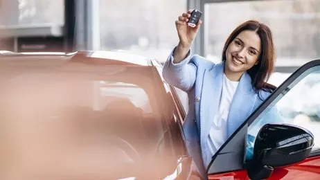 ผู้หญิงยืนถือกุญแจรถข้างรถยนต์สีแดง