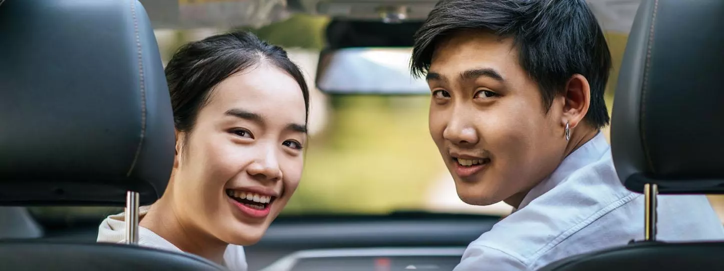 ผู้หญิงและผู้ชายนั่งอยู่ในรถอย่างมีความสุข