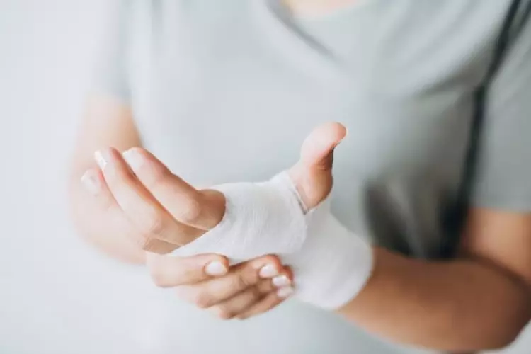 ผู้หญิงมีผ้าพันแผลพันรอบมือ 
