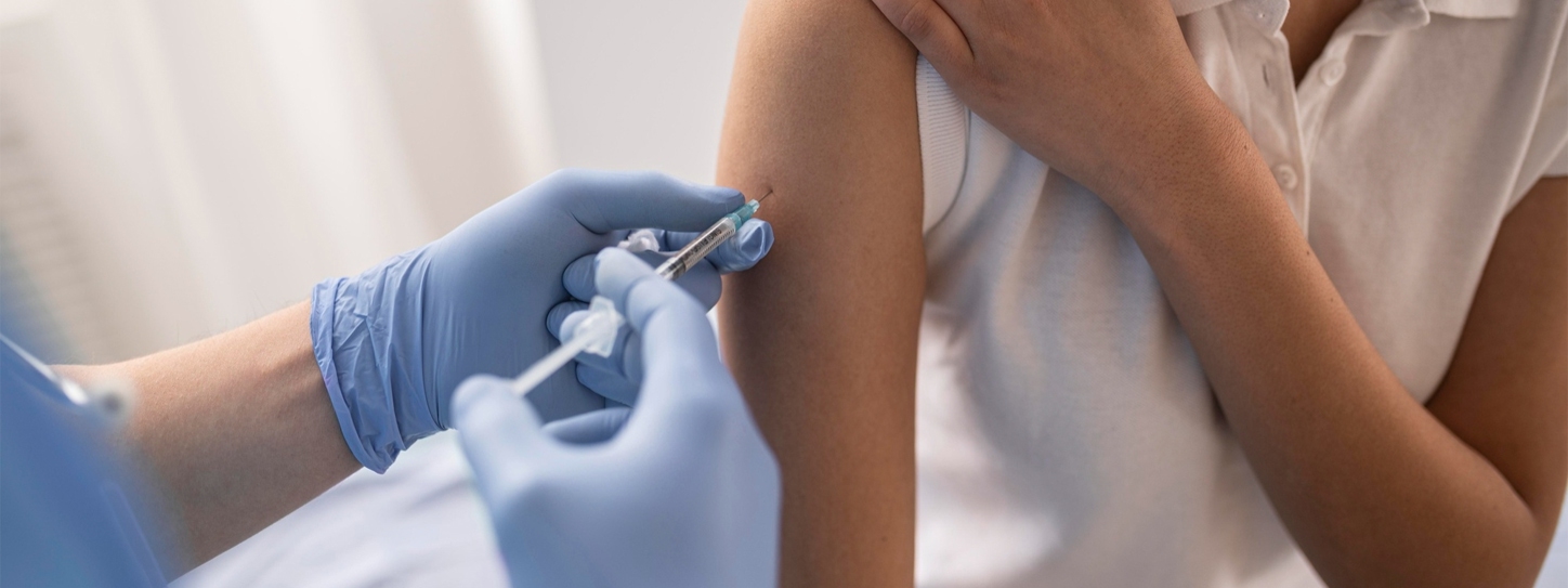 หมอกำลังฉัดวัคซีนบริเวณต้นแขนให้ผู้หญิง