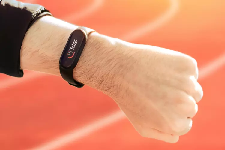 ผู้ชายสวม Fitbit สายรัดข้อมือฟิตเนสขณะซ้อมวิ่ง 