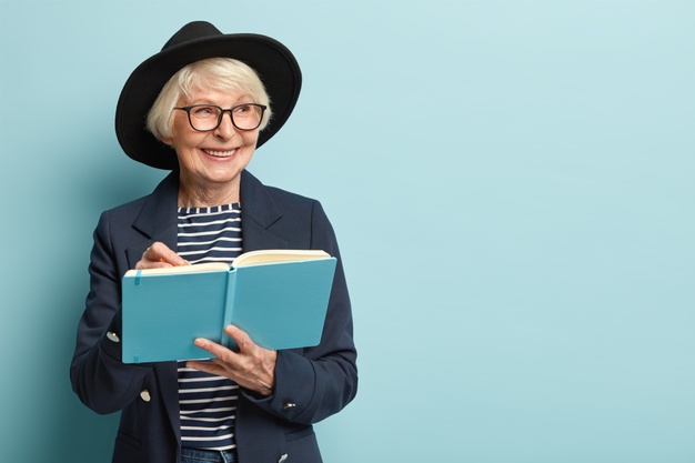 ผู้หญิงมีอายุกำลังเขียนหนังสือด้วยสีหน้ายิ้มแย้ม 