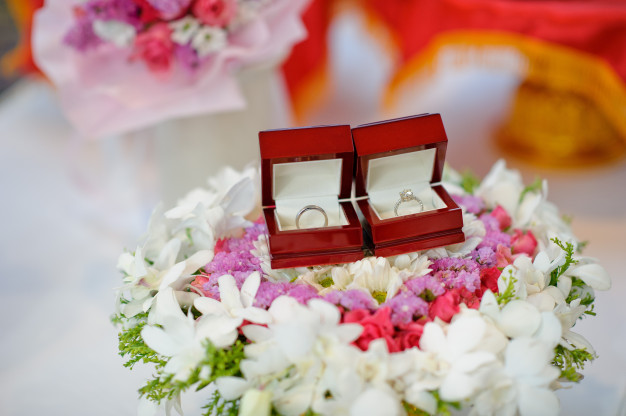แหวนแต่งงานในกล่องแหวนสีแดงวางบนพานดอกไม้