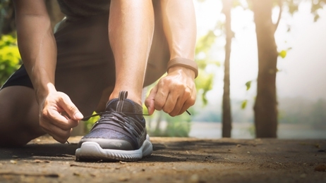 ผู้ชายกำลังนั่งผูกเชือกรองเท้า