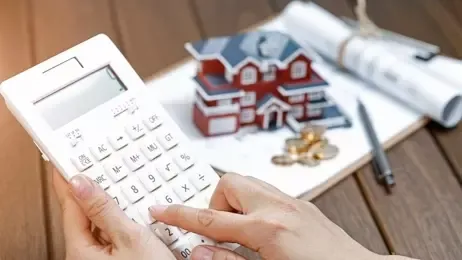 ผู้หญิงใช้เครื่องคิดเลขอยู่หน้าแบบบ้าน