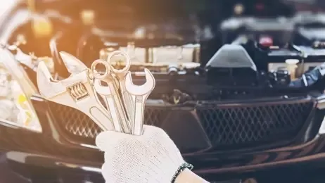ช่างถือชุดประแจอยู่หน้ารถยนต์