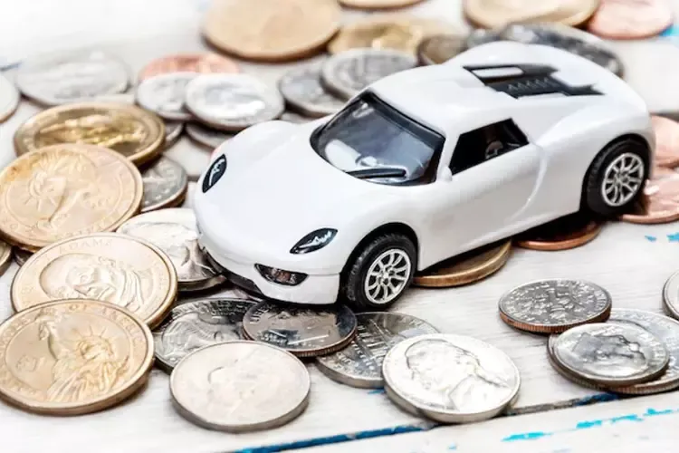 รถของเล่นสีขาววางอยู่บนกองเหรียญ 