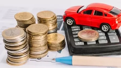 รถของเล่นวางบนเครื่องคิดเลขข้างกองเหรียญ