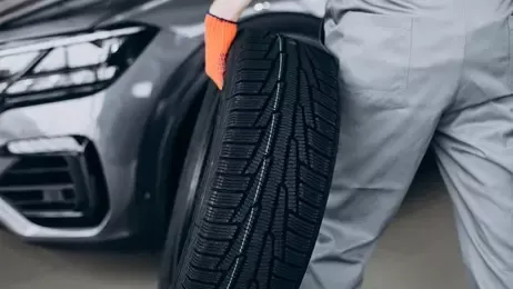 ช่างเดินถือยางรถยนต์มาที่รถ