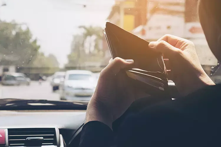 ผู้ชายมองกระเป๋าเงินที่ว่างเปล่าอยู่บนรถ ผู้ชายมองกระเป๋าเงินที่ว่างเปล่าอยู่บนรถ