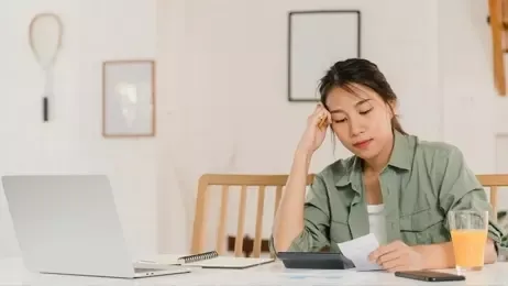 ผู้หญิงบันทึกรายได้และค่าใช้จ่ายที่บ้าน