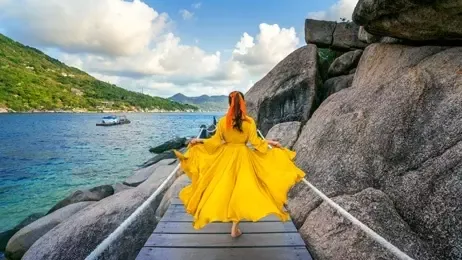 ผู้หญิงเดินบนสะพานไม้ริมทะเล