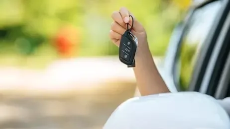 ผู้หญิงนั่งอยู่ในรถและยื่นมกุญแจรถออกจากรถ