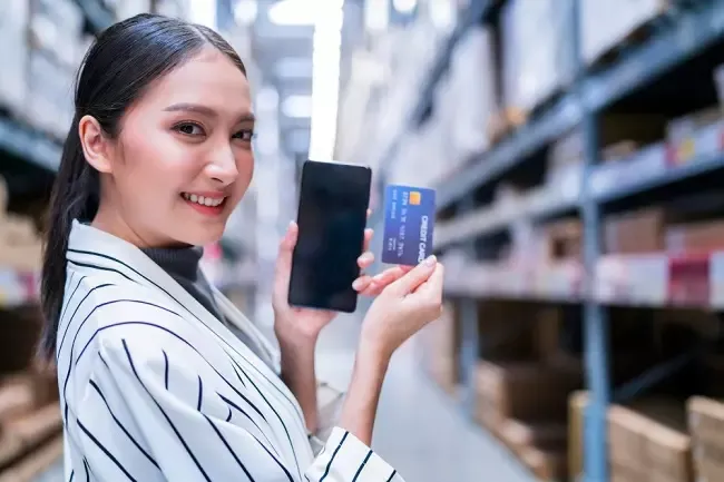 ผู้หญิงถือโทรศัพท์กับบัตรเครดิต