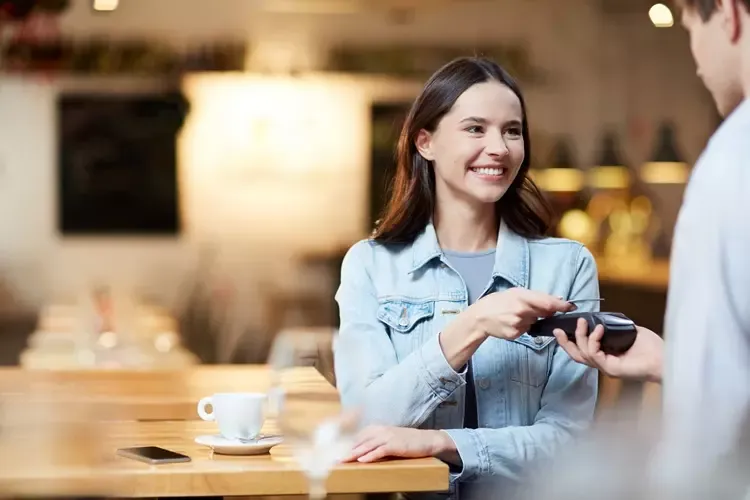 ผู้หญิงใช้บัตรเครดิตชำระเงินที่ร้านอาหาร 
