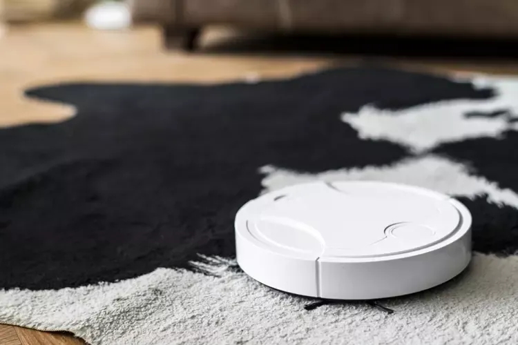 หุ่นยนต์ดูดฝุ่นอยู่บนพรมกลางพื้นห้อง หุ่นยนต์ดูดฝุ่นอยู่บนพรมกลางพื้นห้อง