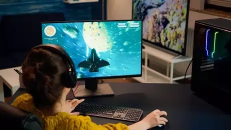 ผู้หญิงนั่งเล่นเกมหน้าจอคอมพิวเตอร์