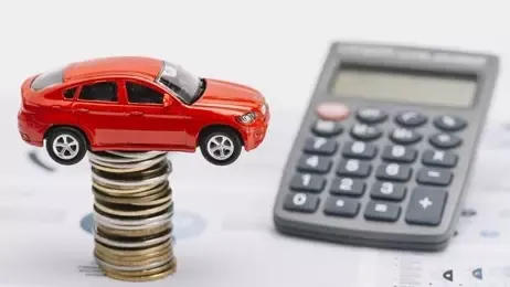 รถของเล่นวางบนกองเหรียญข้างเครื่องคิดเลข