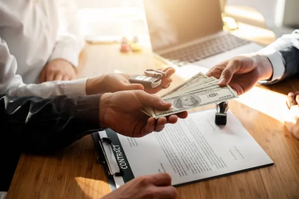 คนกำลังยื่นเงินสดและกุญแจรถ