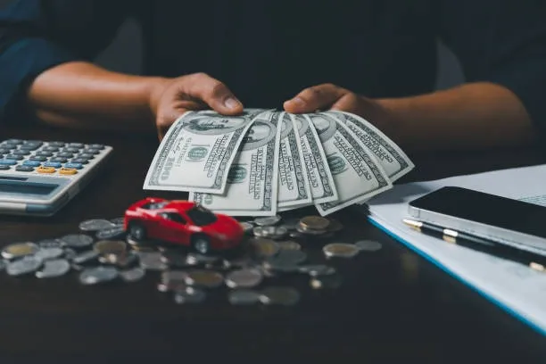 คนถือธนบัตรมีโมเดลรถวางอยู่ด้านหน้า