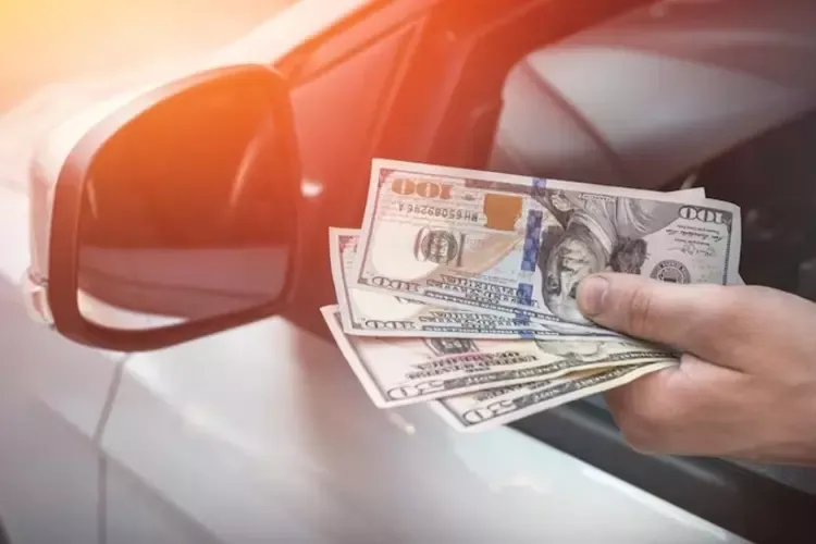 ผู้ชายถือแบงก์ดอลลาร์ขณะนั่งอยู่ในรถ 