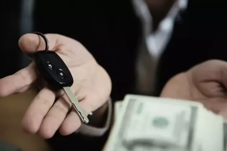 ผู้ชายถือกุญแจรถและธนบัตรในมือ 