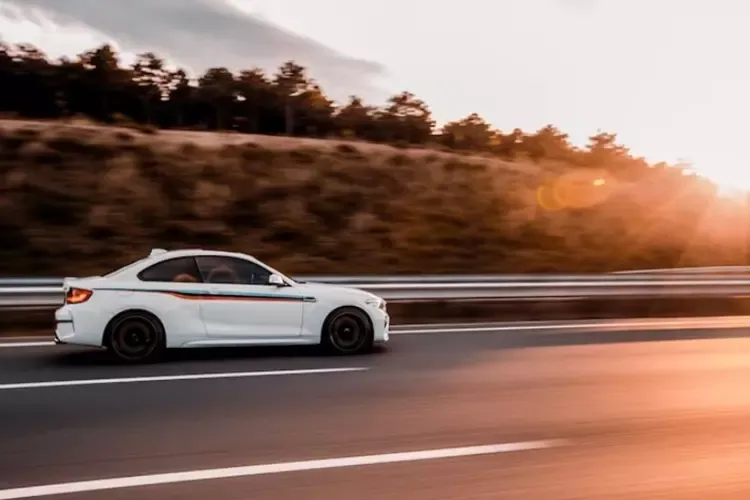 รถเก๋งสีขาวขับบนถนนในยามพระอาทิตย์ตกดิน รถเก๋งสีขาวขับบนถนนในยามพระอาทิตย์ตกดิน