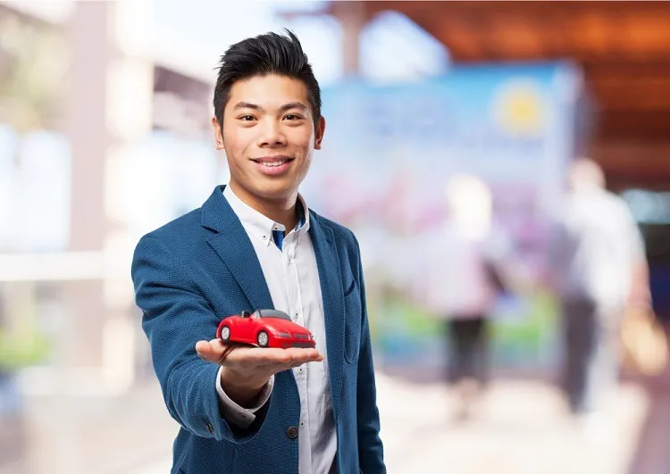 ผู้ชายยืนถือโมเดลรถ