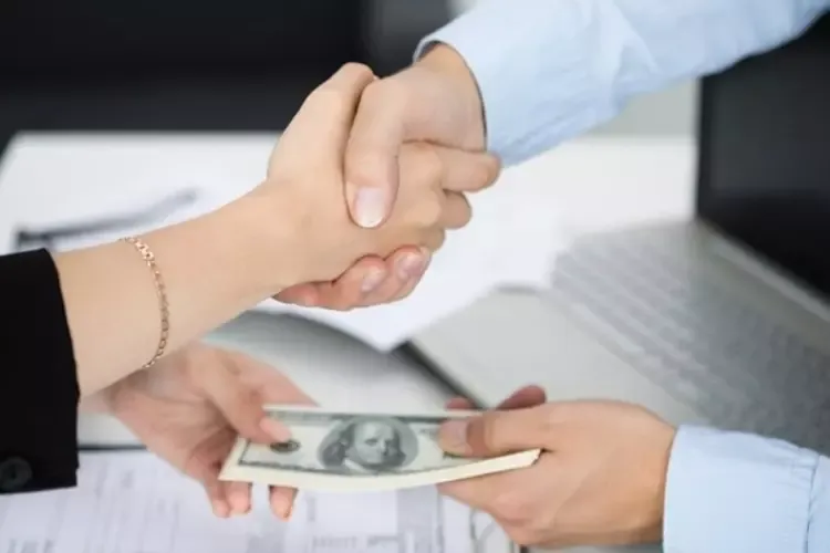 ผู้หญิงและผู้ชายจับมือและถือเงินในมืออีกข้าง 