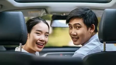 ผู้หญิงและผู้ชายนั่งอยู่ในรถอย่างมีความสุข