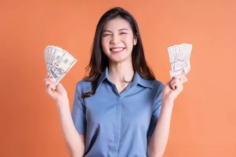 ผู้หญิงยืนยิ้มและถือธนบัตรในมือ 