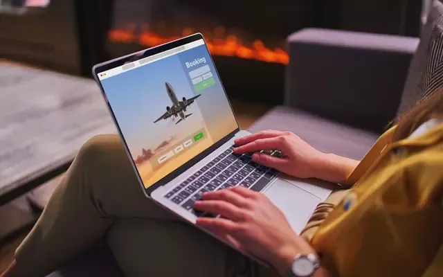 ผู้หญิงใช้แล็ปท็อปจองตั๋วเครื่องบินออนไลน์