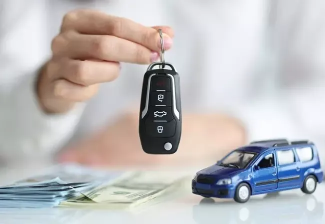 ถือกุญแจไว้หน้ารถของเล่นและเงิน 