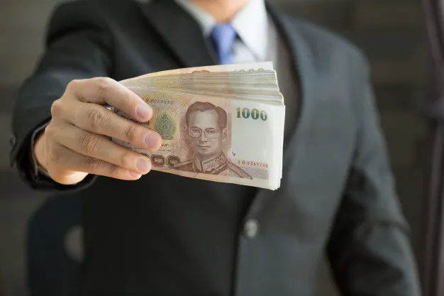 ผู้ชายถือเงินแบงก์หนึ่งพันบาทไทย