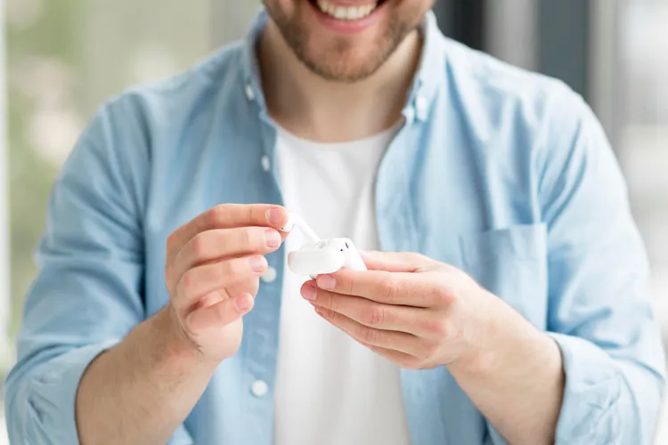 ผู้ชายถือหูฟัง AirPods สีขาวในมือ ผู้ชายถือหูฟัง AirPods สีขาวในมือ