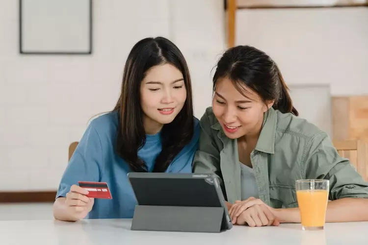 ผู้หญิงสองคนนั่งดูแท็บเล็ตด้วยกันที่บ้าน